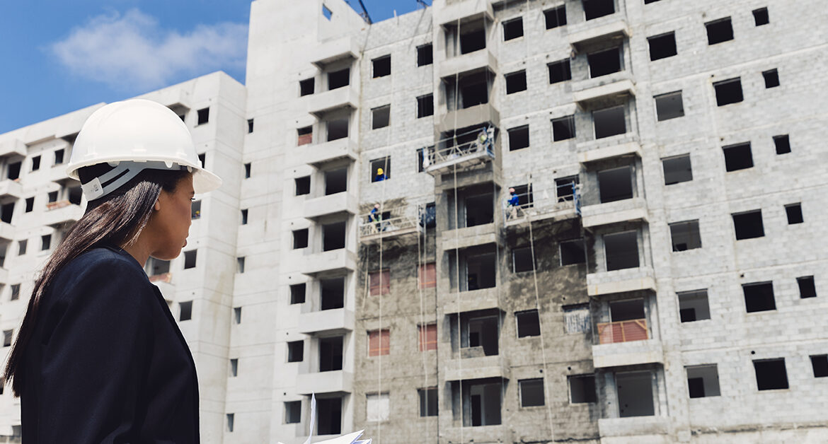 Engenheira observando a obra de construção de um prédio de apartamentos
