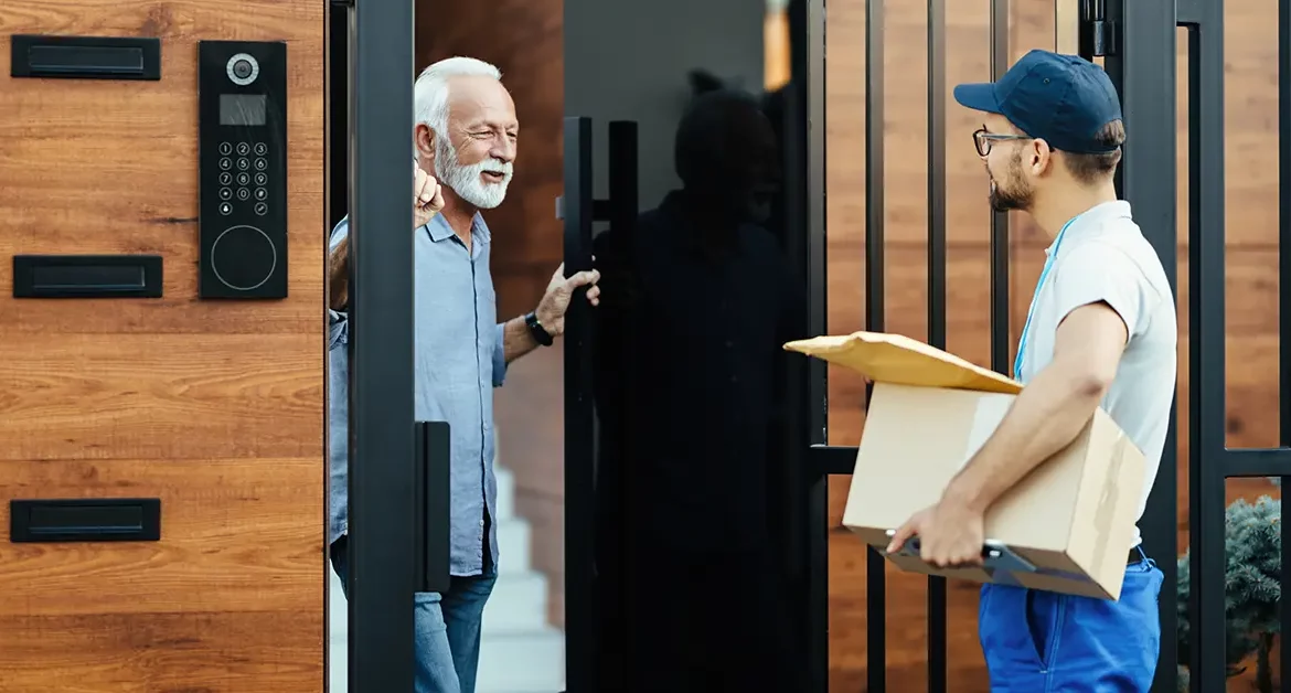 homem sênior feliz se comunicando com um mensageiro que esta entregando pacotes na portaria do prédio
