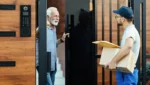 homem sênior feliz se comunicando com um mensageiro que esta entregando pacotes na portaria do prédio